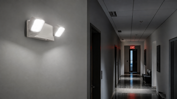 Commercial corridor illuminated by a two-head emergency light and red exit sign during a power outage