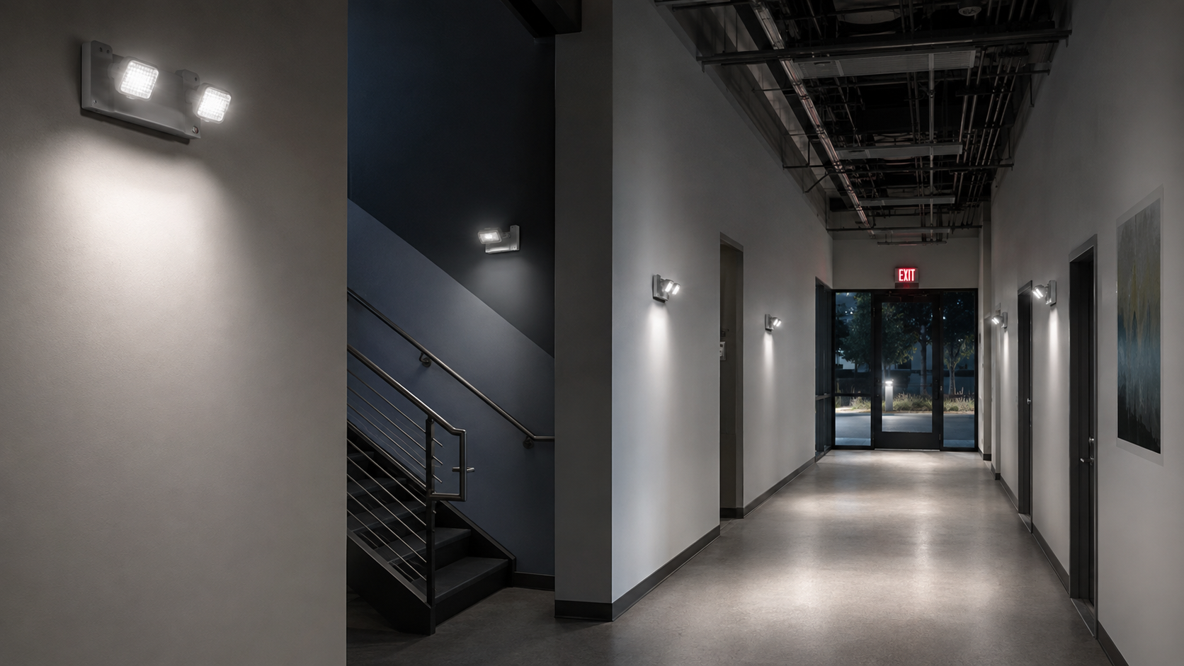 Emergency lights illuminating a commercial corridor, stair landing, and exit discharge path
