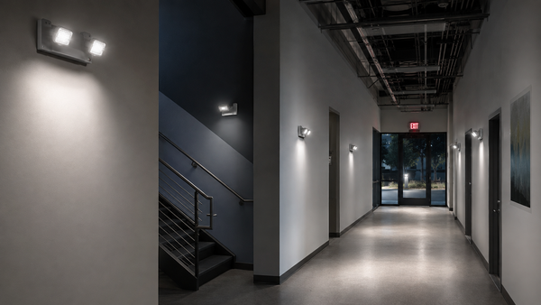 Emergency lights illuminating a commercial corridor, stair landing, and exit discharge path